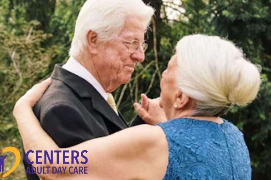 Color photo of an elderly couple dancing joyfully in a garden beneath a large tree.