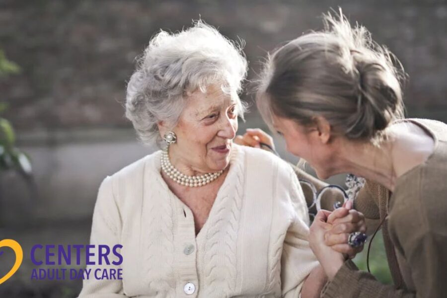 An elderly woman chats warmly with a healthcare professional during a pleasant afternoon conversation.