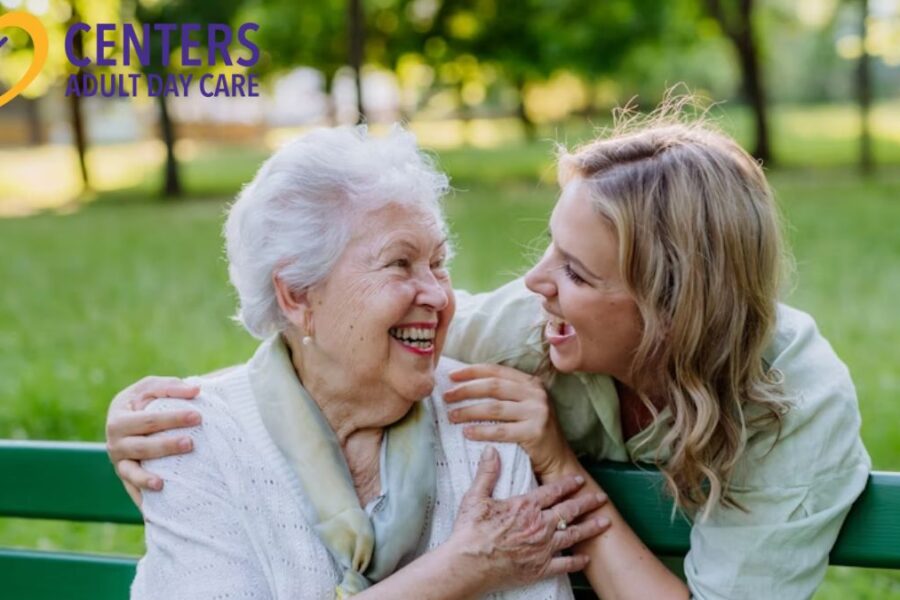 An elderly woman smiles at her adult care specialist while enjoying a respite day in the park, illustrating adult day care services.