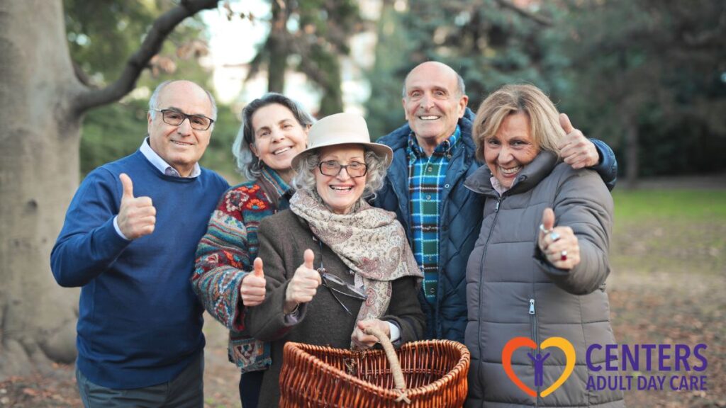 Adult day care in Richmond, a senior group gives a thumbs-up while looking at the camera in the middle of a park.