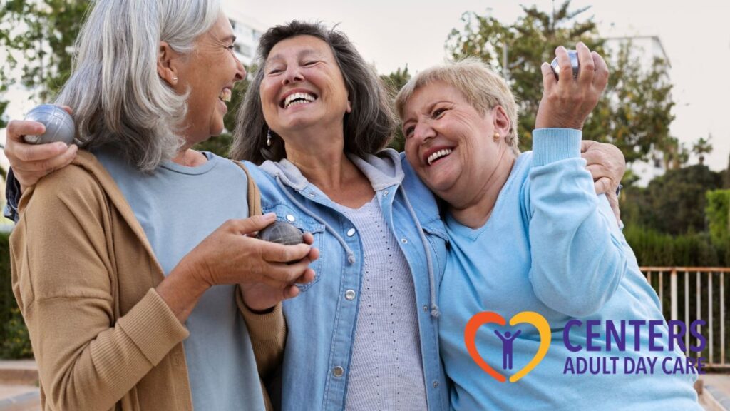 A group of seniors embrace each other outdoors, smiling and enjoying a warm bonding moment, symbolizing the social and emotional benefits of adult day care.
