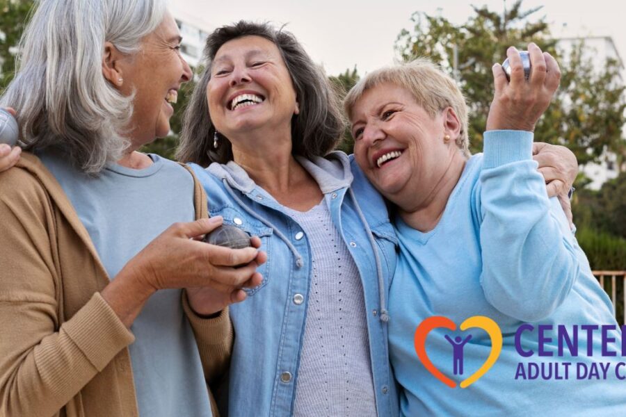 A group of seniors embrace each other outdoors, smiling and enjoying a warm bonding moment, symbolizing the social and emotional benefits of adult day care.